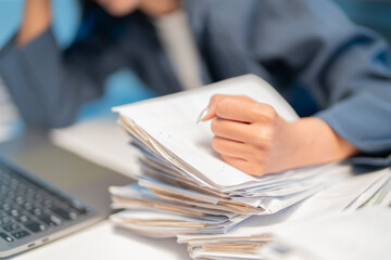 Stressed businesswoman in office feeling exhausted and overwhelmed by heavy workload, surrounded by...