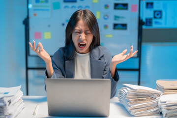 Exhausted asian businesswoman overwhelmed by work stress at cluttered desk late at night, feeling...
