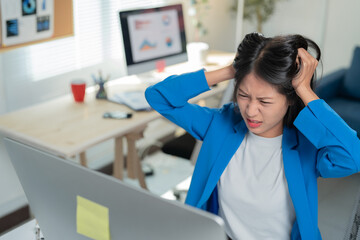 Young businesswoman is feeling the pressure while working at her desk in the office. She is pulling...