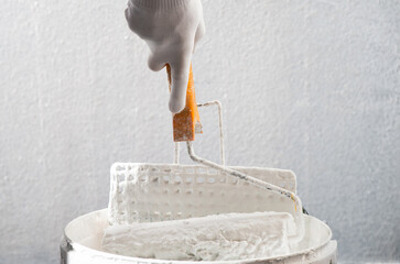 Paint roller on the white color bucket.