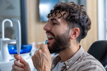 Man with braces meticulously brushing his teeth with interdental brush to maintain oral hygiene