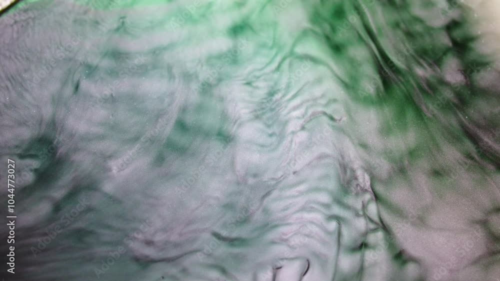 Poster green and white liquids swirl together in a mesmerizing macro shot, creating abstract textures