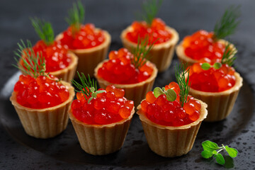 Delicious salmon red caviar in mini tartlets, black  background
