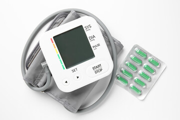 Blood pressure measuring device and pills on white background, top view