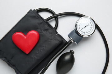 Blood pressure measuring device and heart figure on light grey background, top view
