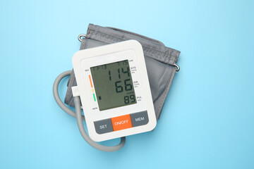 Blood pressure measuring device on light blue background, top view