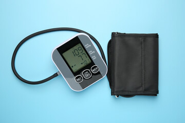Blood pressure measuring device on light blue background, top view