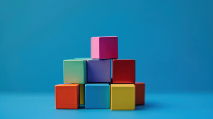 Fototapeta premium Colorful building blocks arranged in playful pyramid shape against vibrant blue background, creating cheerful and creative atmosphere
