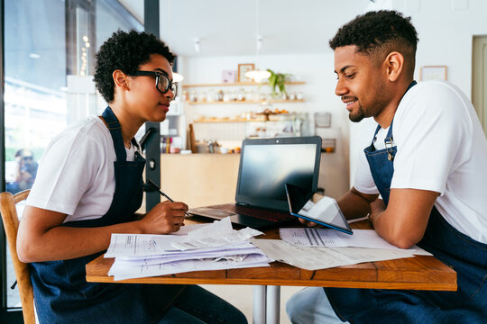 Bakery, portrait of hispanic black man and woman in cafe calculating costs and taxes  - Small business owners tracking income and expenses, checking balance and doing financial plan