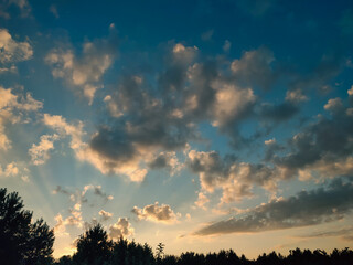Vivid orange clouds over the forest at sunset. Colorful clouds on the dramatic sunset sky.
