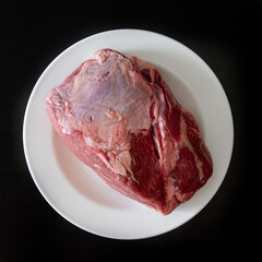 A piece of raw meat is placed neatly on a clean white plate, ready for cooking or serving in a delicious meal preparation