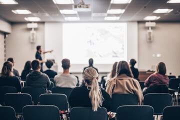 Speaker giving a talk in conference hall at business event. Rear view of unrecognizable people in...