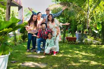 Indian family of six happily posing for a group photo during a camping trip, capturing cherished...