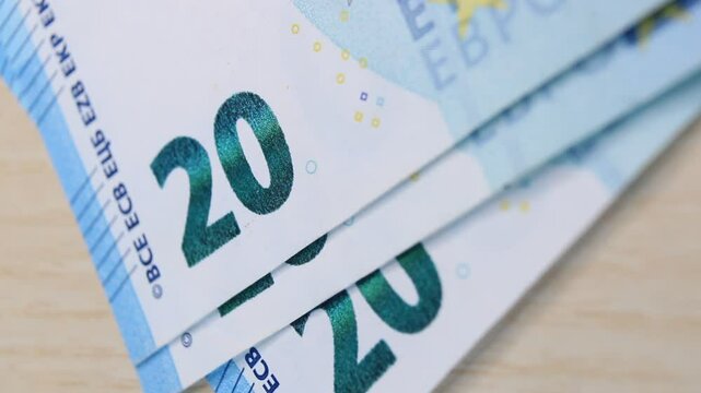 A man counts out 20 euro banknotes and places them one by one on a beige office desk