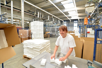 woman works in the shipping department of a company and packs styrofoam components into packages for the customer