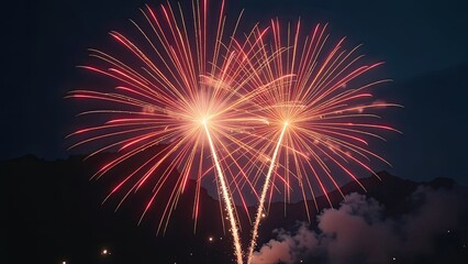 Fototapeta premium Banner Two bright fireworks explosions light up the night sky above a silhouette of mountains, captured in a wide shot during a festive celebration.