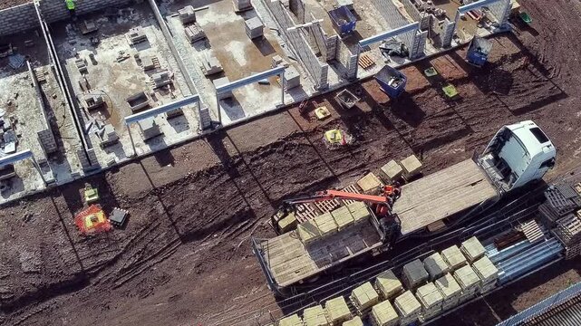 Construction site in action with heavy machinery unloading materials in a bustling urban area