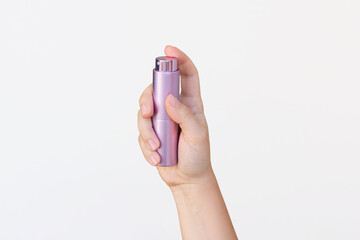 Young woman's hand holding lilac atomiser for perfume isolated on a white background. Portable...