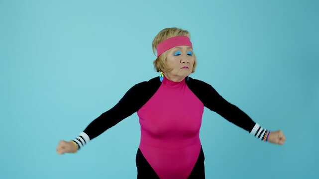 Happy and funny senior old woman wearing sportswear clothing on colorful background- Modern cool fancy grandmother portrait doing fitness workout, concepts about elderly, sport, healthy lifestyle.
