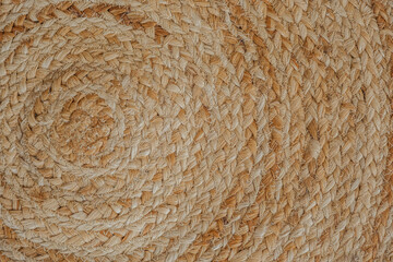 Woven straw mat with intricately designed spiral patterns in natural tones