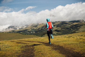 Fitness woman runner running at high altitude grassland mountain top road