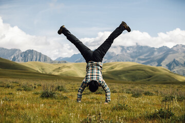 Woman hiker doing a handstand on high altitude mountain top grassland