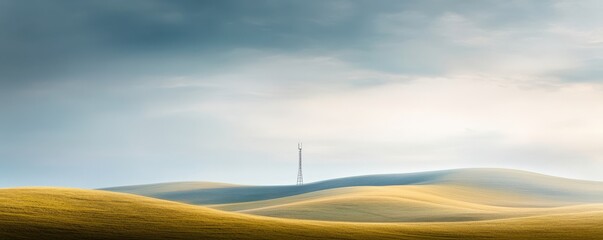 Obraz premium Serene landscape with gentle hills and a solitary tower under a dramatic sky, perfect for evoking calm and isolation.