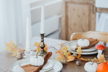 Cozy autumn dining table set with decorative pumpkins and fall leaves in a warm indoor setting