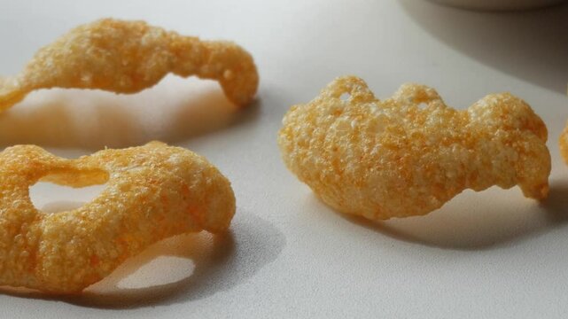 Panning closeup haunting molded orangey potato and corn crisps figures. Halloween related.