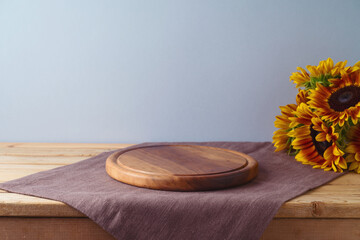 Empty wooden round board with sunflowers on wooden table. Thanksgiving background mock up for...