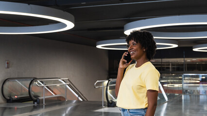 Afro woman talking on mobile phone at illuminated parking garage