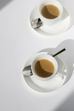 Two Cups of Freshly Made Espresso with Crema on White Table Background. Cafe Still Life.