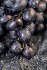 fresh grapes are lying on black paper