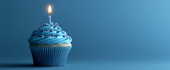 A single blue cupcake with a lit candle on top, on a blue background.