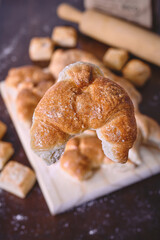 Freshly Baked Croissant on a Wooden Board with Baking Ingredients in the Background