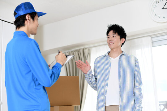 部屋で会話をする男性作業員と若い男性客