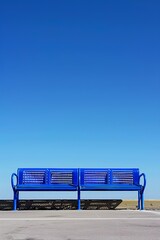Vibrant blue bench against clear sky in minimalist urban landscape. Concept of blue Monday