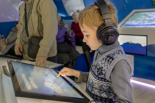Immersion in world of technology: child wearing headphones in front of an interactive screen