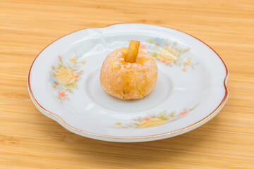 Plate with a panellet on a wooden surface. Panellets are traditional sweets for All Saints' Day in Catalonia, the Balearic Islands, Levante and Aragon.