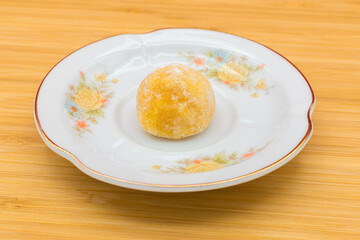 Plate with a panellet on a wooden surface. Panellets are traditional sweets for All Saints' Day in Catalonia, the Balearic Islands, Levante and Aragon.