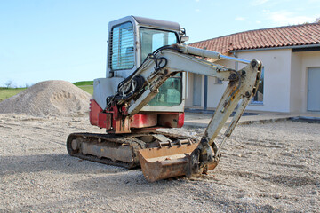 Mini pelle devant la maison neuve en construction
