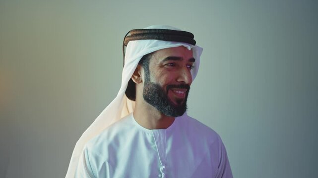Handsome saudi arabian middle-eastern man with traditional thwab portrait in studio on colored backgrounds and gel colored lights.	
