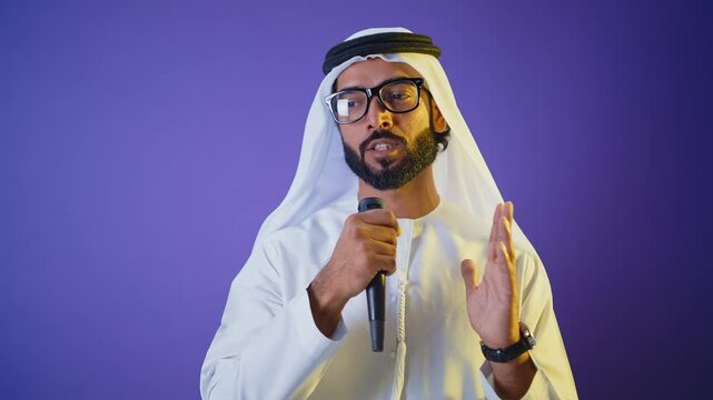 Handsome saudi arabian middle-eastern man with traditional thwab portrait in studio on colored backgrounds and gel colored lights.	
