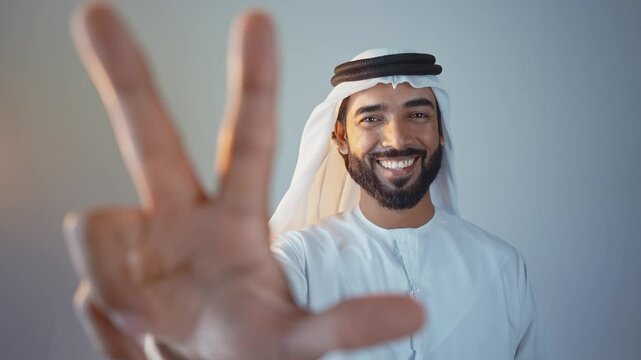 Handsome saudi arabian middle-eastern man with traditional thwab portrait in studio on colored backgrounds and gel colored lights.	
