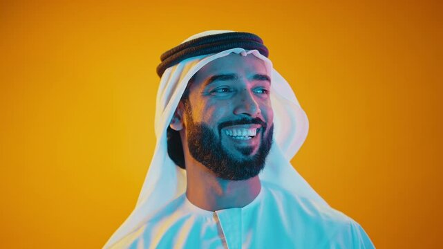 Handsome saudi arabian middle-eastern man with traditional thwab portrait in studio on colored backgrounds and gel colored lights.	
