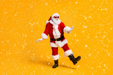 Full size photo of funky santa claus with grey beard listen magic x-mas christmas music headset dance party wear cap headwear sunglass isolated bright shine color background