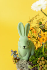 A whimsical green bunny nestled among vibrant flowers against a sunny yellow backdrop in a vibrant spring setting