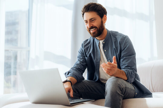 Smiling, attractive bearded Latin man wearing casual clothes using laptop, having video conference