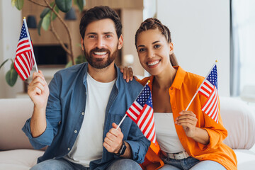 Happy, excited Hispanic man and woman, supporters holding American flags rejoicing election results.