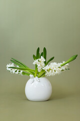 Elegant white hyacinth flowers arranged in a minimalist vase on a soft green background, bringing serenity to any space